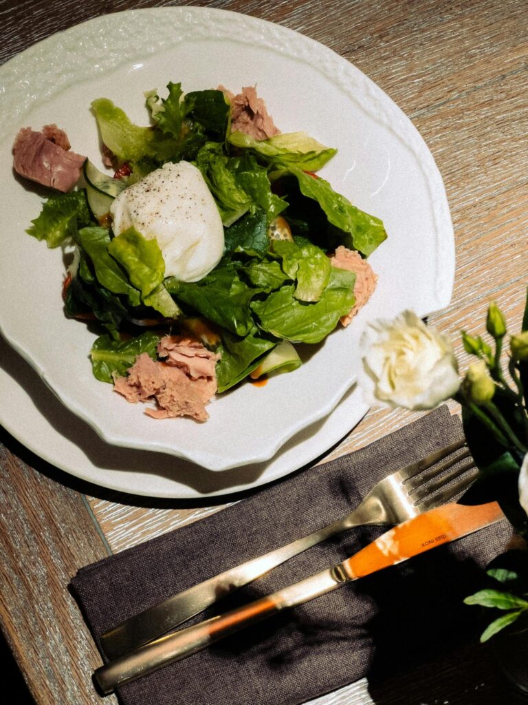 A delicious tuna salad topped with a poached egg served on a rustic wooden table, perfect for healthy dining.