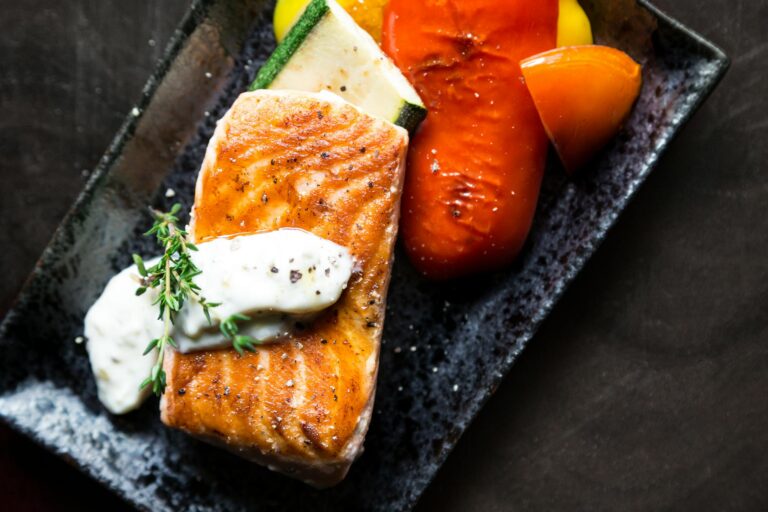 Delicious grilled salmon served with roasted vegetables and herb sauce.