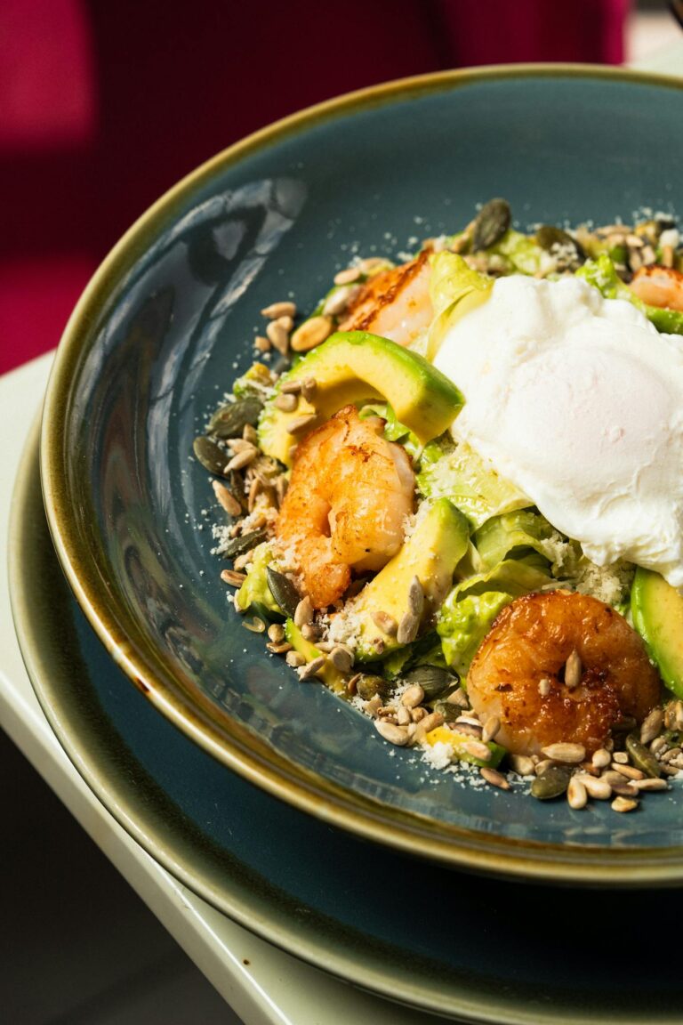 Delicious shrimp avocado salad topped with a poached egg, vibrant and nutritious.